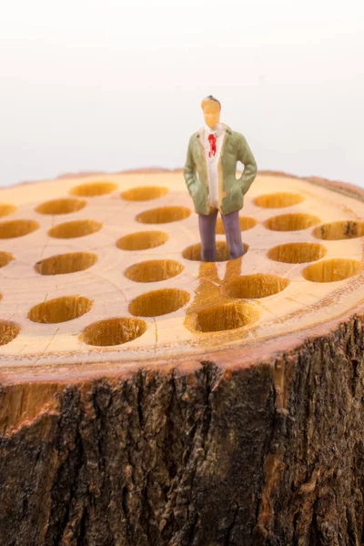 Little man figurine places on wooden log