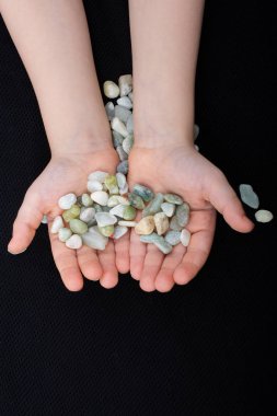 Siyah zemin üzerinde çakıl taşları tutan eller