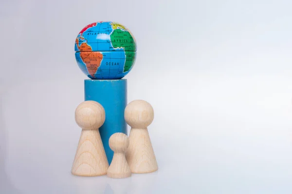 Wooden figurines of people aand a mini globe on white background