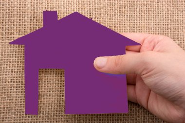 Tuvalin arka planında bir bez evi tutan el.