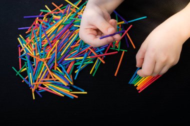 Beyaz arka planda yaratıcılık için renkli tahta çubuklarla oynayan çocuk