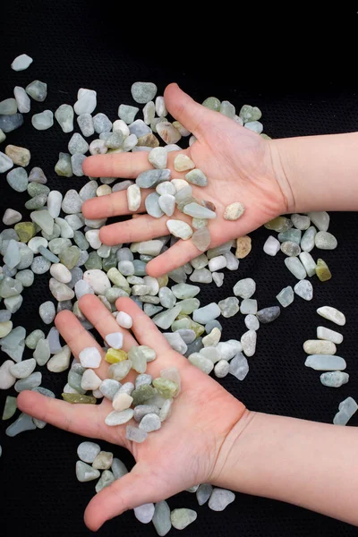 Clean stone pebbles gravels under hand on a black background
