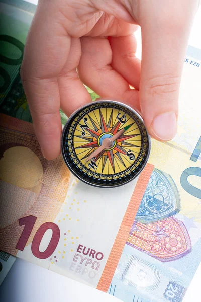 Compass in hand on Euro banknotes with Euro currency finance direction