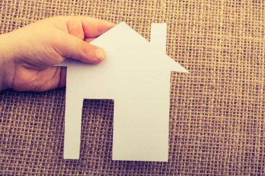 Tuvalin arka planında bir bez evi tutan el.