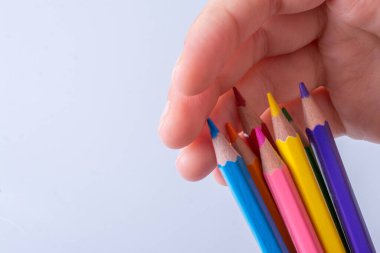 Beyaz arkaplana yerleştirilmiş el ele tutuşan kalemler