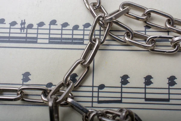 楽譜付きの紙に置かれた金属製の鎖 — ストック写真