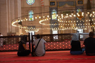 Büyük bir camide dairesel avizenin üzerindeki parlak lambalar.