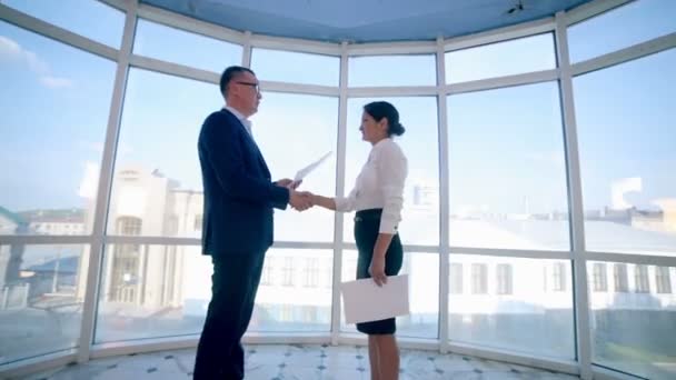 Бизнес, концепция недвижимости. Мужчина и женщина пожимают друг другу руки в офисе . — стоковое видео
