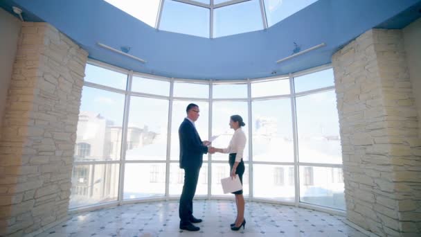 Бизнес, концепция недвижимости. Мужчина и женщина пожимают друг другу руки в офисе . — стоковое видео