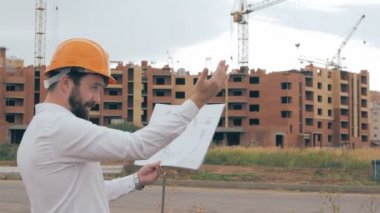İnşaat sahasında plan ile mühendislik. Kask içinde baş mimar.