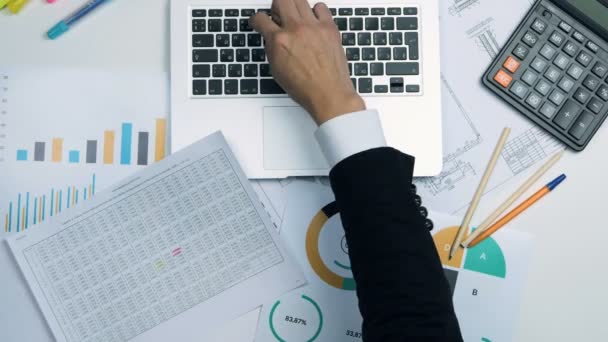 Businessman working at office desk on his laptop and financial reports. Top view. — Stock Video