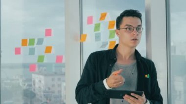 Casual genç işadamı penceresindeki Office yapışkan notlar yazma beyin fırtınası.
