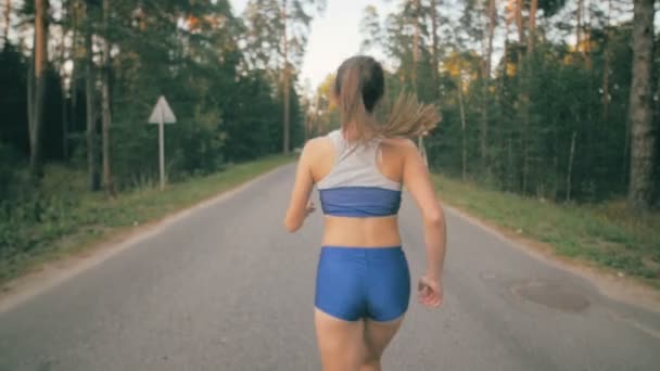 Treino de fitness. Uma jovem a correr. Corredor feminino correndo em uma estrada do parque. Treino de fitness. Movimento lento . — Vídeo de Stock