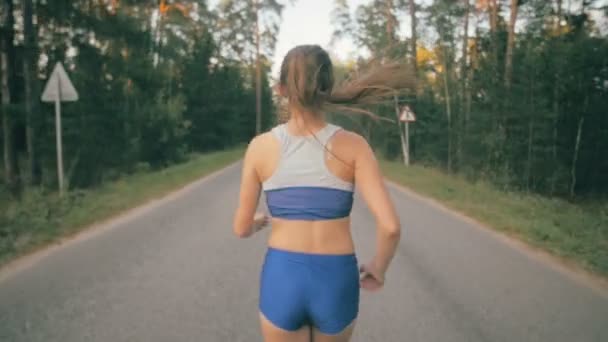 Primer plano del zapato de correr y las piernas del corredor. Vista lateral trasera de una atleta entrenando fuera en la carretera en el parque . — Vídeo de stock