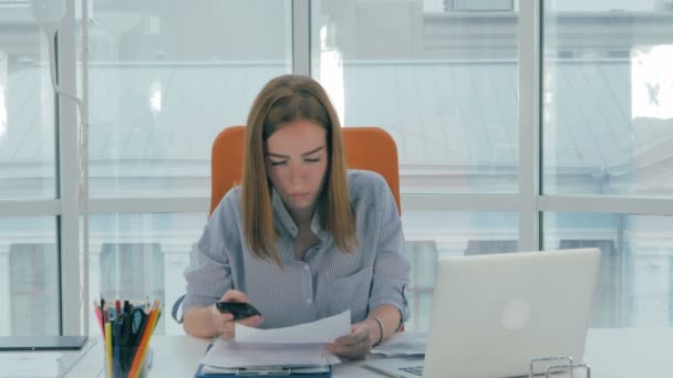 Mladá podnikatelka na stůl s telefonem a počítačem v moderní kanceláři.