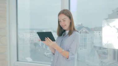Tablet bilgisayarda çalışarak ve gülümseyen genç iş kadını.