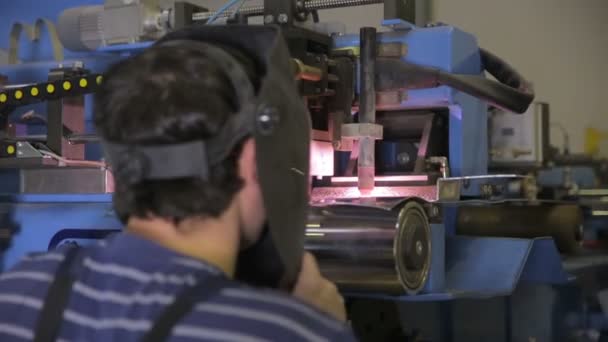 Worker controls plasma welding machine, welding metal parts. — Stockvideo