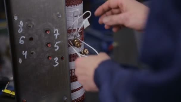 Factory worker assembling electric equipment - transformer - on assembly Line. High voltage components Manufacturing. — Αρχείο Βίντεο