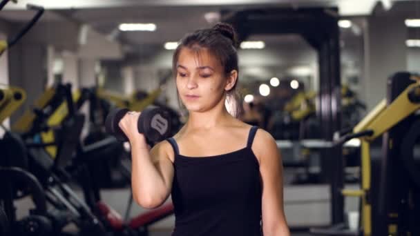 Jonge schoonheid sport vrouw doen oefeningen met halters in de sportschool. Een gezonde levensstijl concept. — Stockvideo
