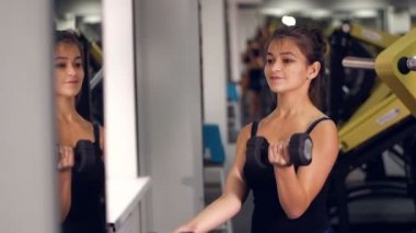 Genç güzellik spor kadın spor salonunda dumbbells ile yapıyor. Bir sağlıklı yaşam konsepti.