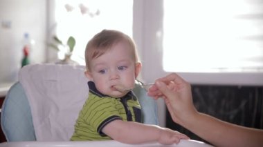 Bebek sandalyede oturan, etrafa meraklı şirin bebek. Annesi onu çok güzel bir yıl eski bir kaşıkla besleme.