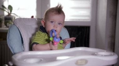 Erkek bebek bebek sandalyede oturan bir oyuncakla oynamak. Bir yaşında bebek.