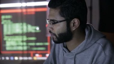 Erkek Arapça hacker bilgisayar karanlıkta kesmek. Yüzünde yansıtan bilgisayar kodu.