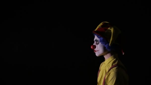 Scary clown with an axe in a dark room. Frightening jester, clown, buffoon. — Stock Video