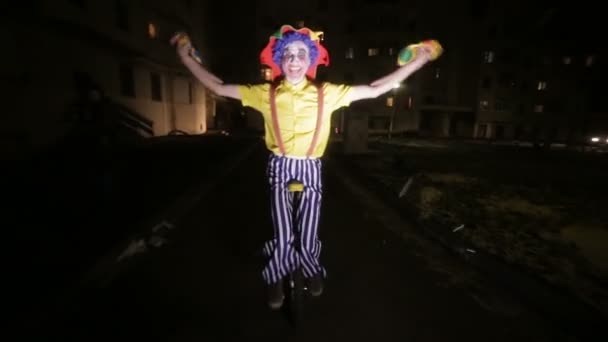 Smutný klaun děsivá jízda na jednokolek v tmavé ulici. — Stock video