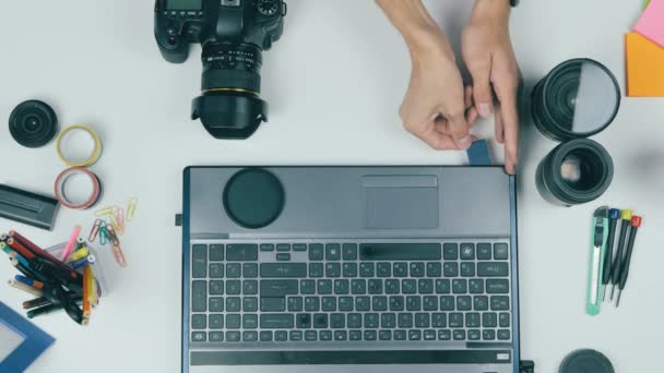 Fotograf designer arbetar med kamera och bärbar dator vid sitt skrivbord. — Stockvideo