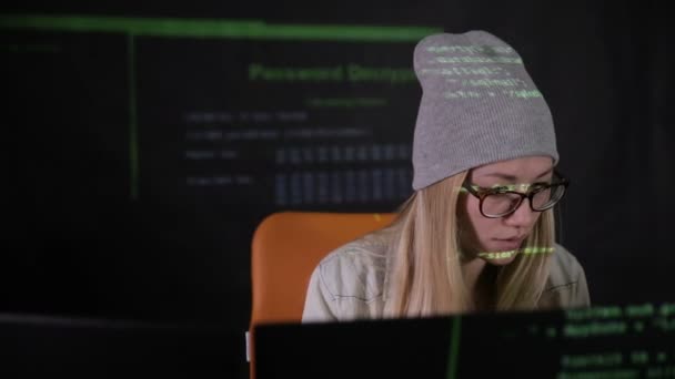 Une pirate travaillant à l'ordinateur la nuit tombée. Projection de code binaire sur son visage. Tir de curseur. Vue de face .