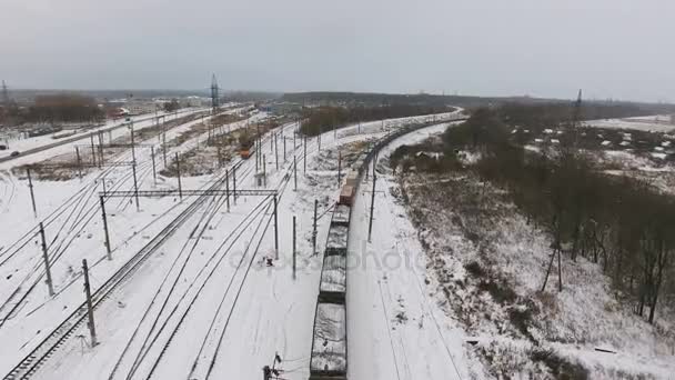 Груз, грузовой поезд, проходящий через железнодорожную станцию зимой. Аэросъемка . — стоковое видео