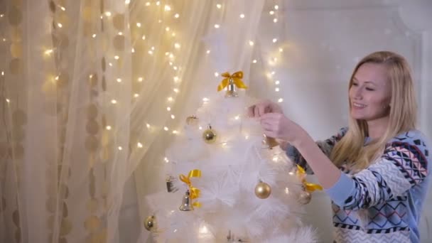 Девушка кладет игрушку на новогоднюю елку, готовится к празднованию Рождества . — стоковое видео