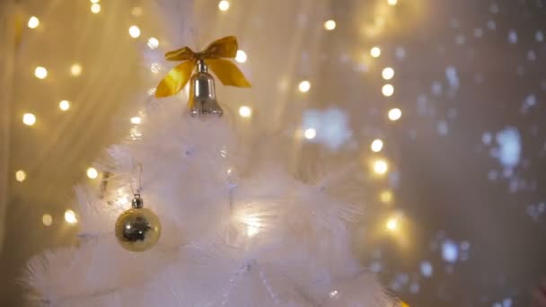 Chica poniendo un juguete en un árbol de año nuevo, preparándose para la celebración familiar de Navidad . — Vídeo de stock