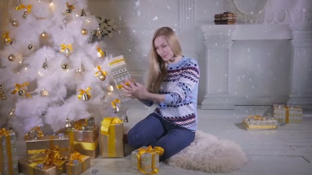 Kerstcadeaus. Emotionele mooi meisje in de buurt van de kerstboom shows aanwezig, enthousiast over nieuwe jaar vakantie komen. — Stockvideo