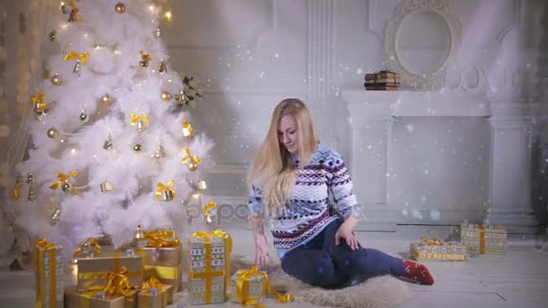 Christmas presents. Emotional pretty girl near christmas tree shows present, excited about new year holidays coming. — Stock Video