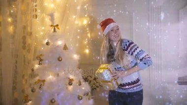 Mutlu gülümseyen genç kadın Noel ağacının yanında hediye ile dans sunar. Yeni yıl, Eve, Xmas kavramı.