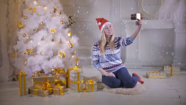 Young pretty woman near Christmas tree making selfie during Christmas Eve. New year selfie Photo. — Stock Video