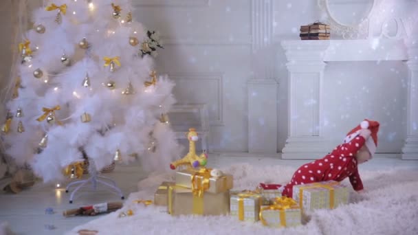 Baby spielt in der Nähe des Weihnachtsbaums. während der Neujahrsfeier. — Stockvideo
