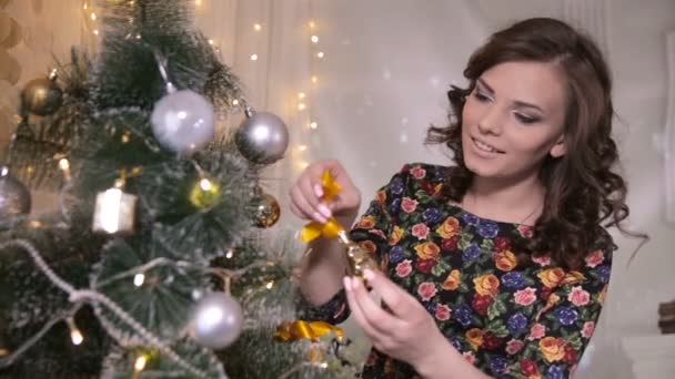 Όμορφη κοπέλα, νεαρή γυναίκα διακόσμηση του Χριστουγεννιάτικου δέντρου, βάλτε νέο έτος παιχνίδια και μπάλες για το χριστουγεννιάτικο δέντρο. — Αρχείο Βίντεο