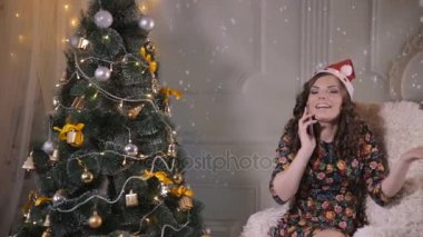 Tarafından cep telefonu Noel ağacı yakınındaki genç sevimli yakışıklı kız konuşuyor. Noel Kutlamaları.