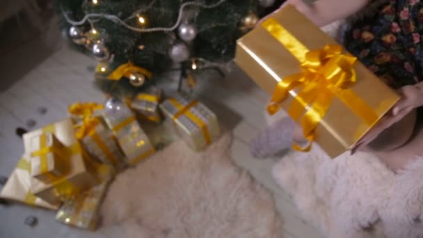 Vrouwelijke handen geeft een geschenk, kerstcadeau in camera. Cadeaus onder de kerstboom. Schuifregelaar schot. — Stockvideo