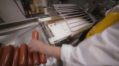 Et incelik üretimi. İşçi el çalışır auotmated üretim hattı sosis ve et ürünleri.