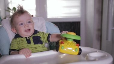 Erkek bebek bebek sandalyede oturan bir oyuncakla oynamak. Bir yaşında bebek.