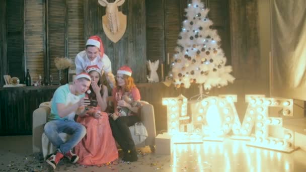 Sorglös tonåring vänner fira jul nära dekorerad jul tittar på en ny ansökan i smartphone. — Stockvideo
