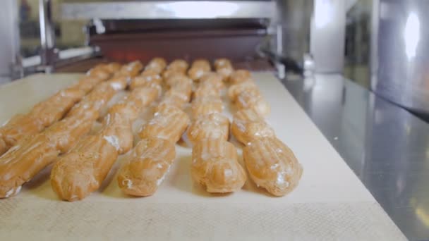 Transportör linje med rörliga Eclairs. Eclairs, kakor, bakverk, dessert produktionslinje. — Stockvideo