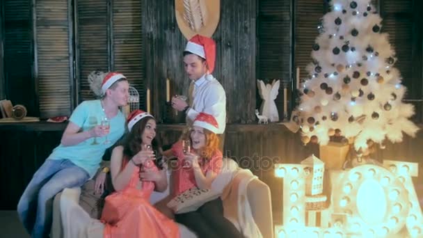 Cheerful group of friends near the Christmas decorated tree, drink alcohol from wine glasses - laughing, having fun. — Stock Video