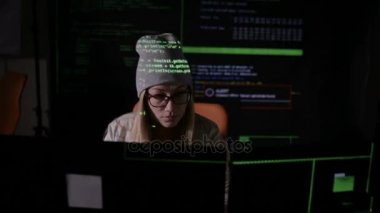 Bilgisayar geceleri karanlık odada kullanan ciddi genç kadın. Yüzüne yansıyan bilgisayar kodu.