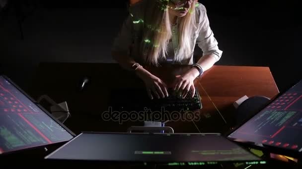 Mujer joven y seria usando la computadora por la noche en el cuarto oscuro. Código informático reflejado en su cara . — Vídeos de Stock