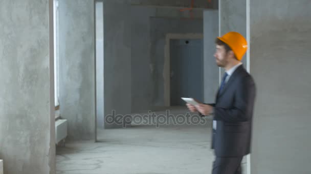 Razoador, engenheiro de construção, empresário dentro de um novo prédio inspecionando canteiro de obras usando tablet . — Vídeo de Stock